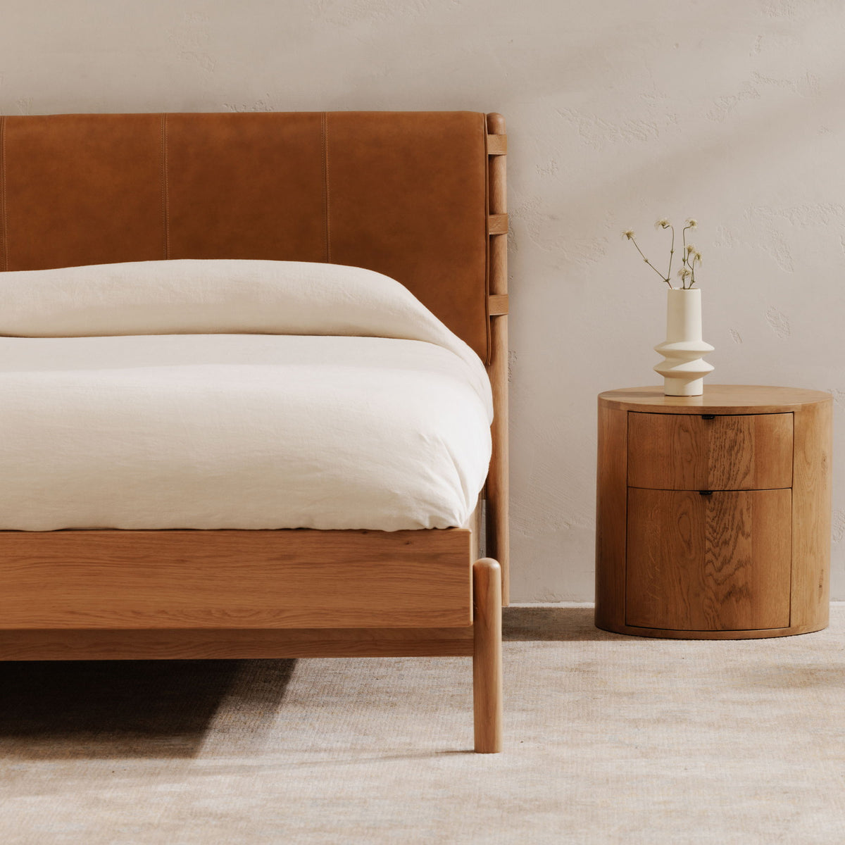 Queen bed with brown upholstered headboard and light wood frame, white bedding