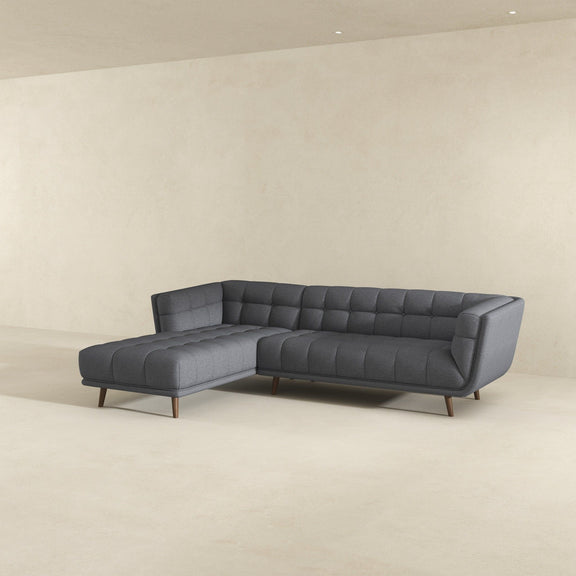 Dark gray tufted L-shaped sectional sofa with chaise seating and cushioned back