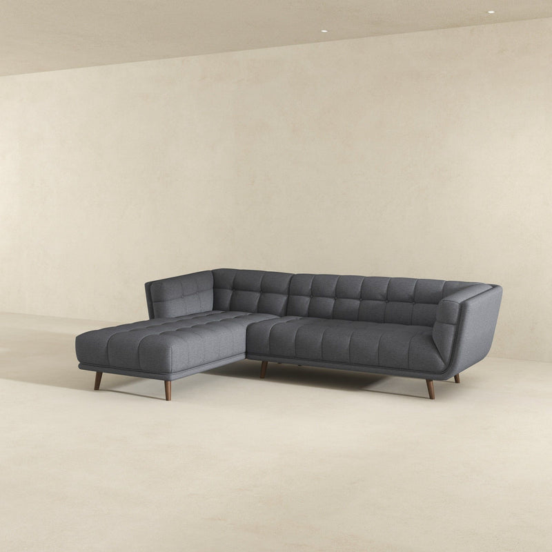 Dark gray tufted L-shaped sectional sofa with chaise seating and cushioned back