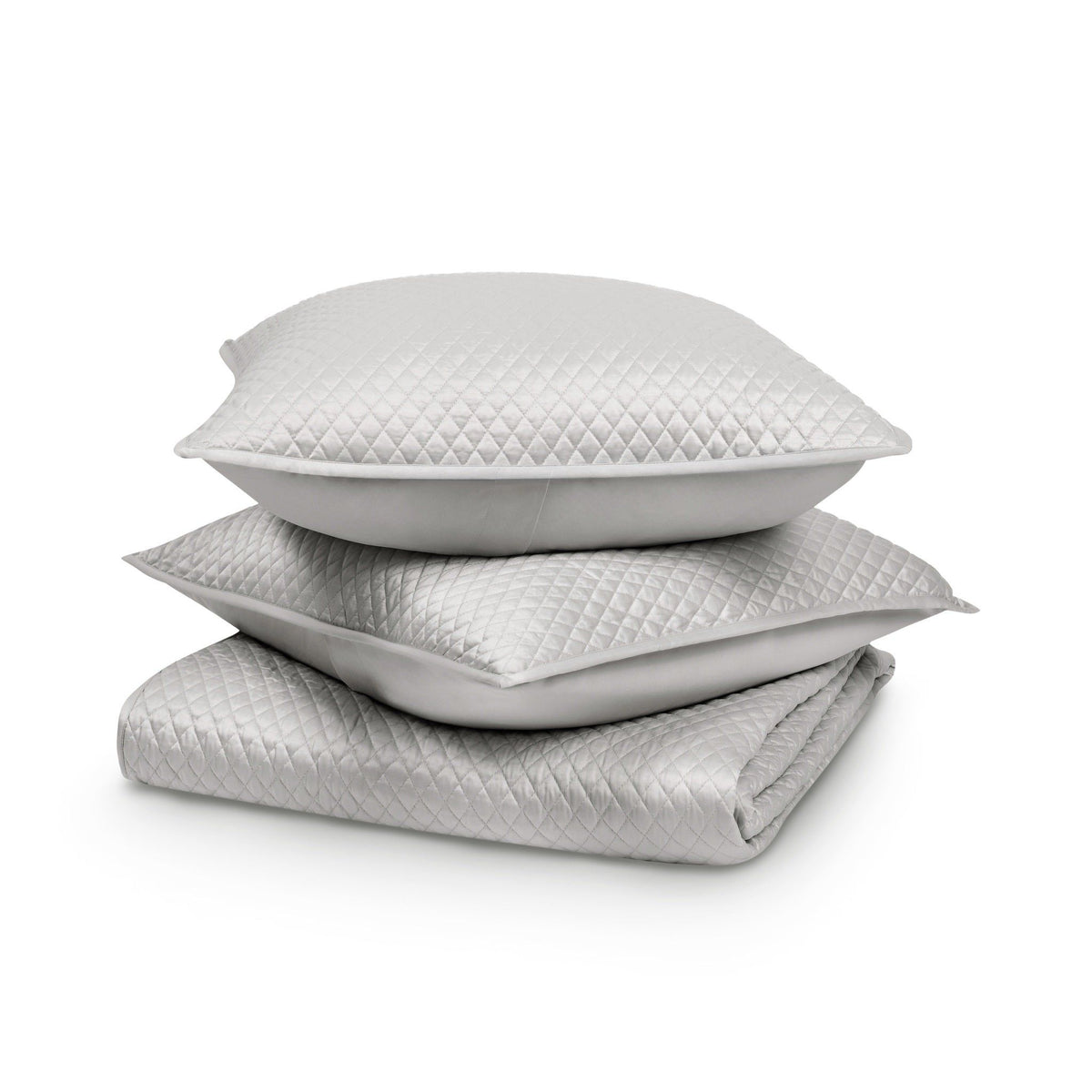 Stacked white diamond-quilted pillow shams with smooth inner cushion inserts