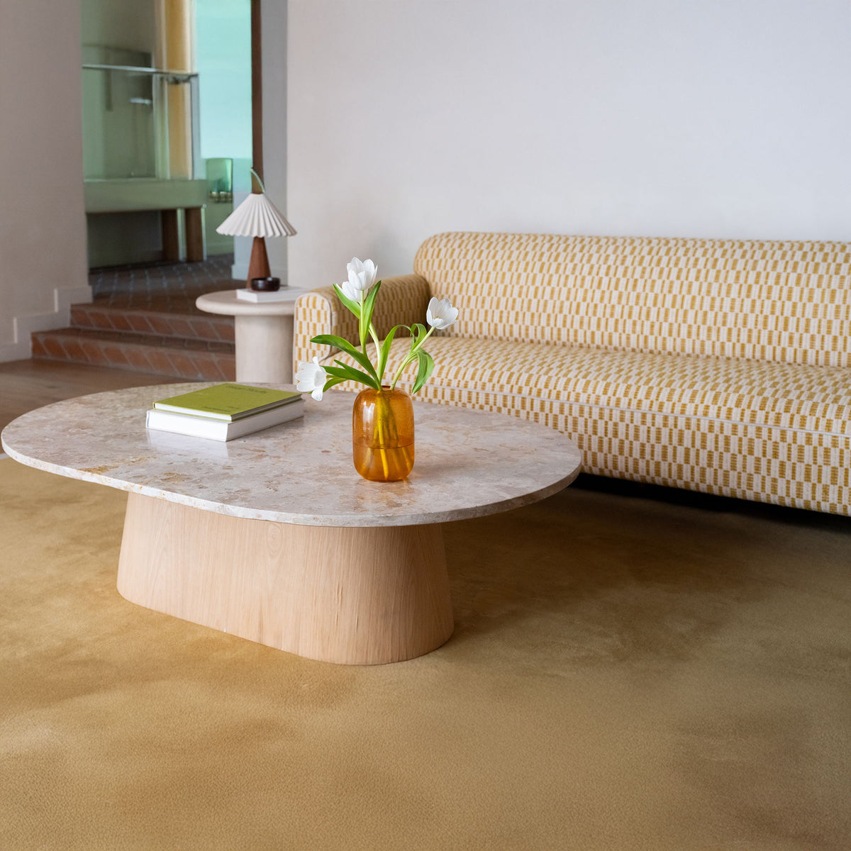 Round coffee table with mottled light stone top and light wood pedestal base