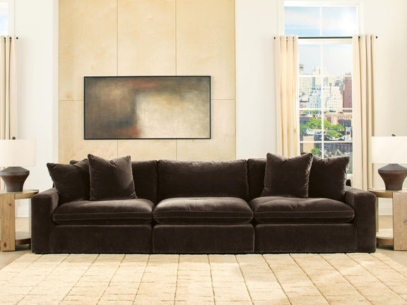 Dark brown 3-seat sectional sofa with four accent pillows in an open room