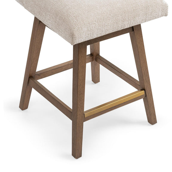 Counter-height swivel stool base detail with light beige upholstery, wooden legs and gold-tone stretcher.