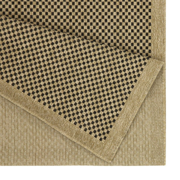 Light brown area rug corner detail with black-and-brown check border and textured weave