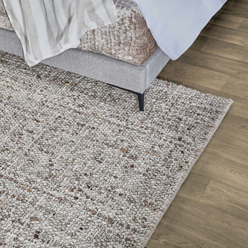 Speckled wool rug with short pile, placed on hardwood floor