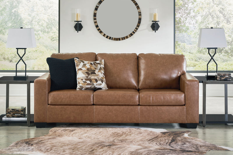 Brown upholstered sofa with three seat sections and two decorative pillows