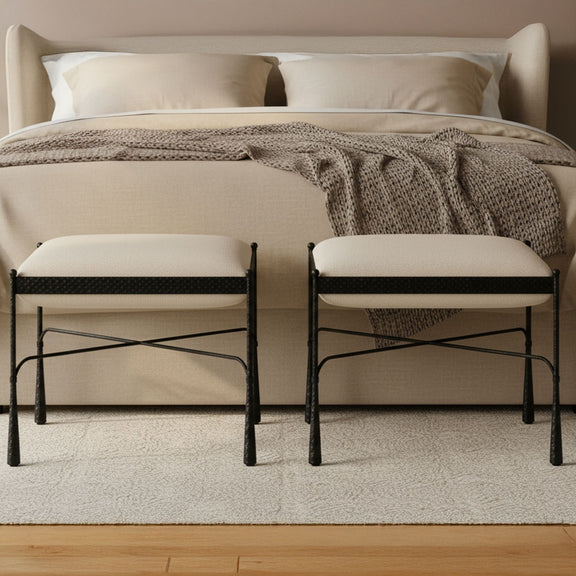 Two cream upholstered stools with black metal legs, placed side by side