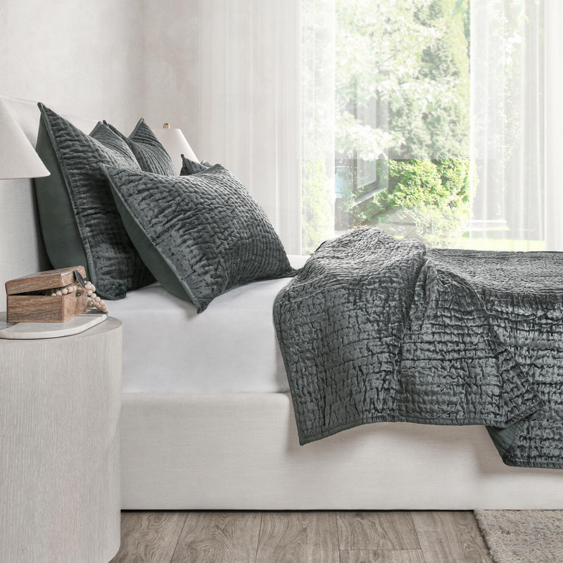 Charcoal velvet quilt set with textured square pillows on bed