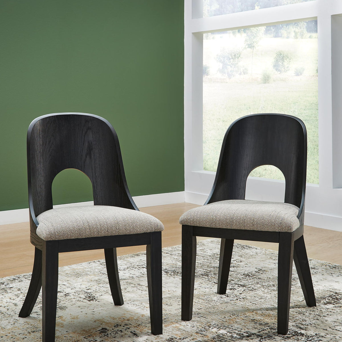 Two black dining side chairs with beige seat cushions and arched open backs