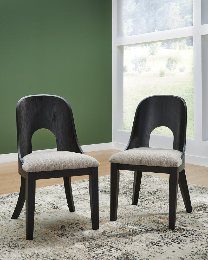 Two black dining side chairs with beige seat cushions and arched open backs