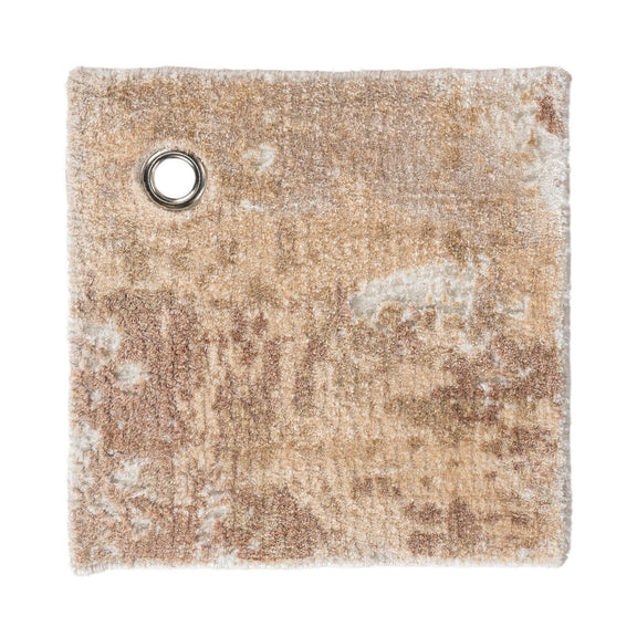 Tan and cream rug swatch with round metal grommet; distressed abstract texture.