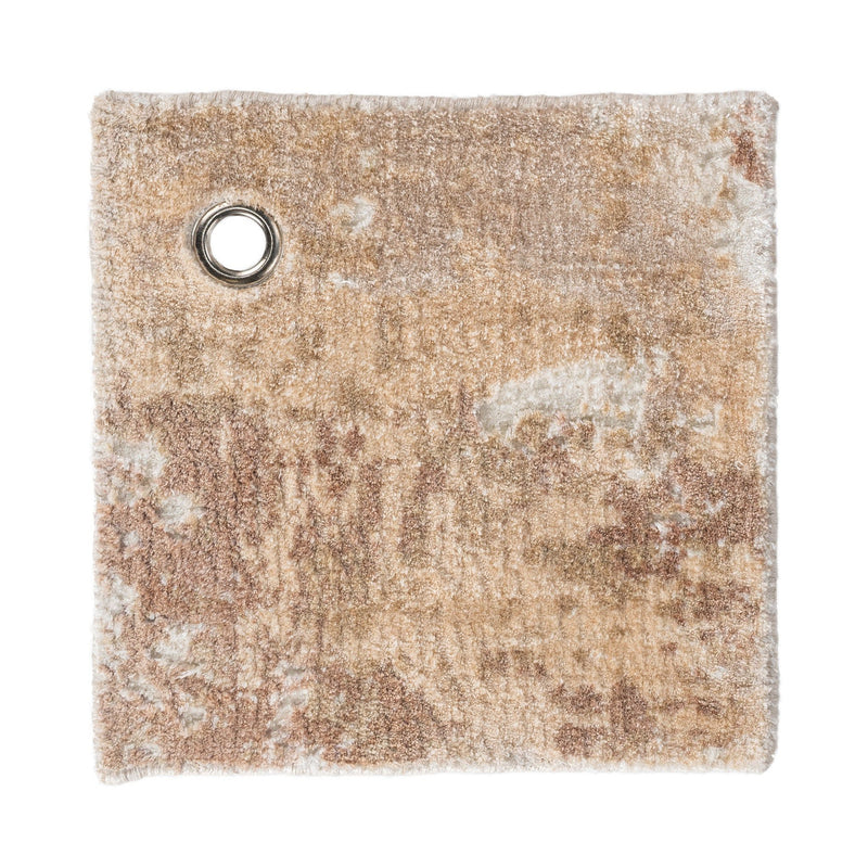 Tan and cream rug swatch with round metal grommet; distressed abstract texture.