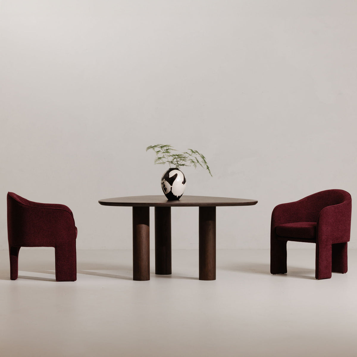 Plum upholstered dining chair with curved back and armrests, shown beside a table