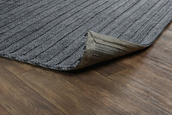 Charcoal flatweave rug corner detail with woven texture on wood floor