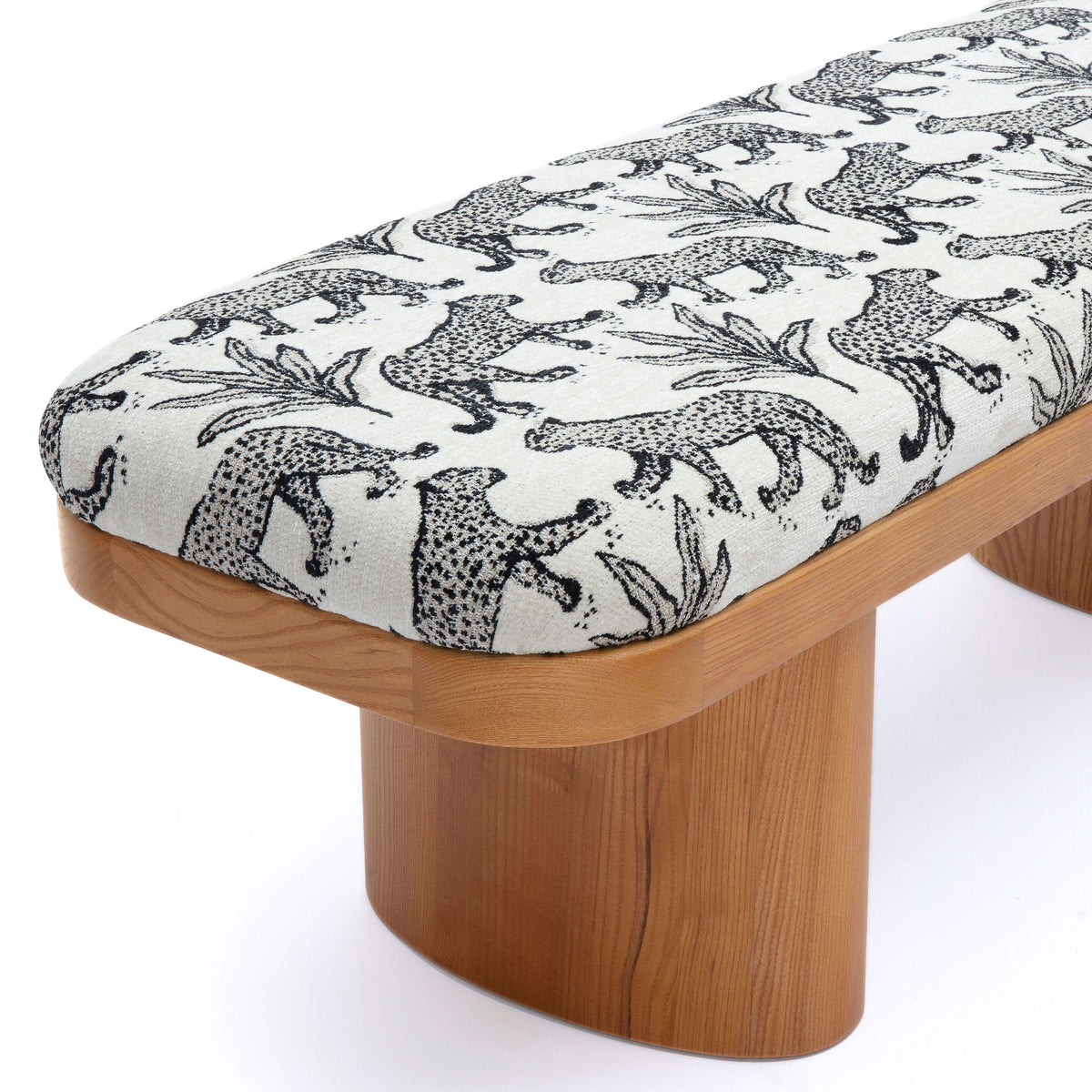 Leopard jacquard bench close-up: white fabric with black animal silhouettes, light wood base