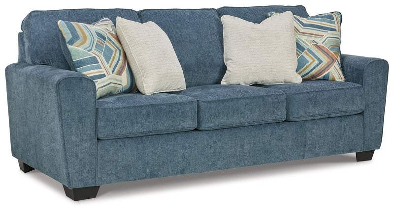 Blue fabric sofa with four throw pillows and square arms, front three-cushion style