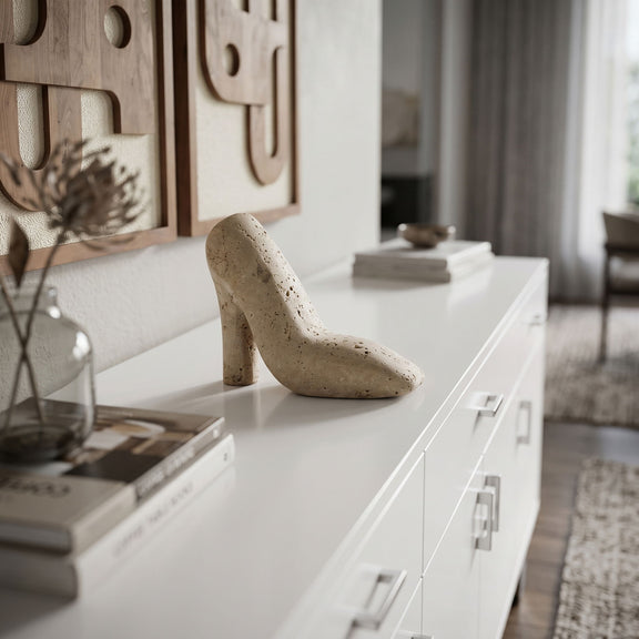 Beige high-heel shoe tabletop sculpture on a white console, speckled stone texture