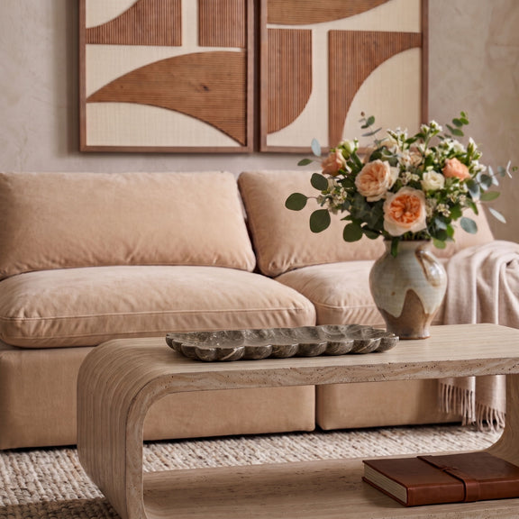 Beige travertine tray on table beside books, styled with sofa behind