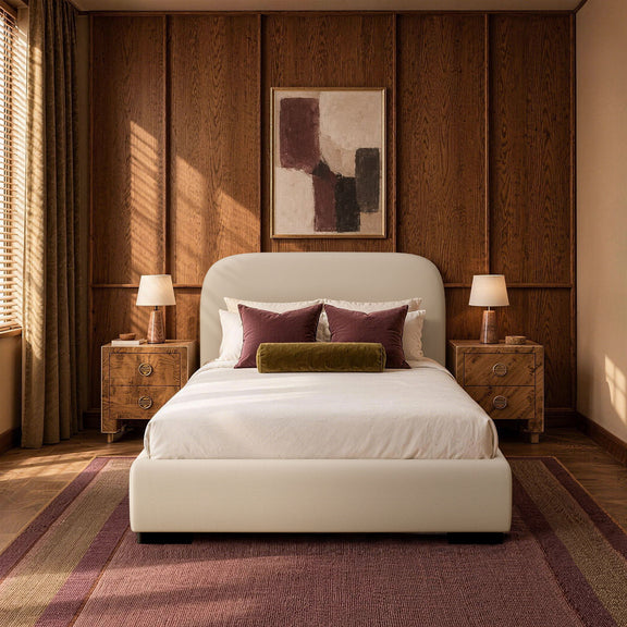 Beige upholstered bed with rounded headboard, styled pillows, and neatly made bed