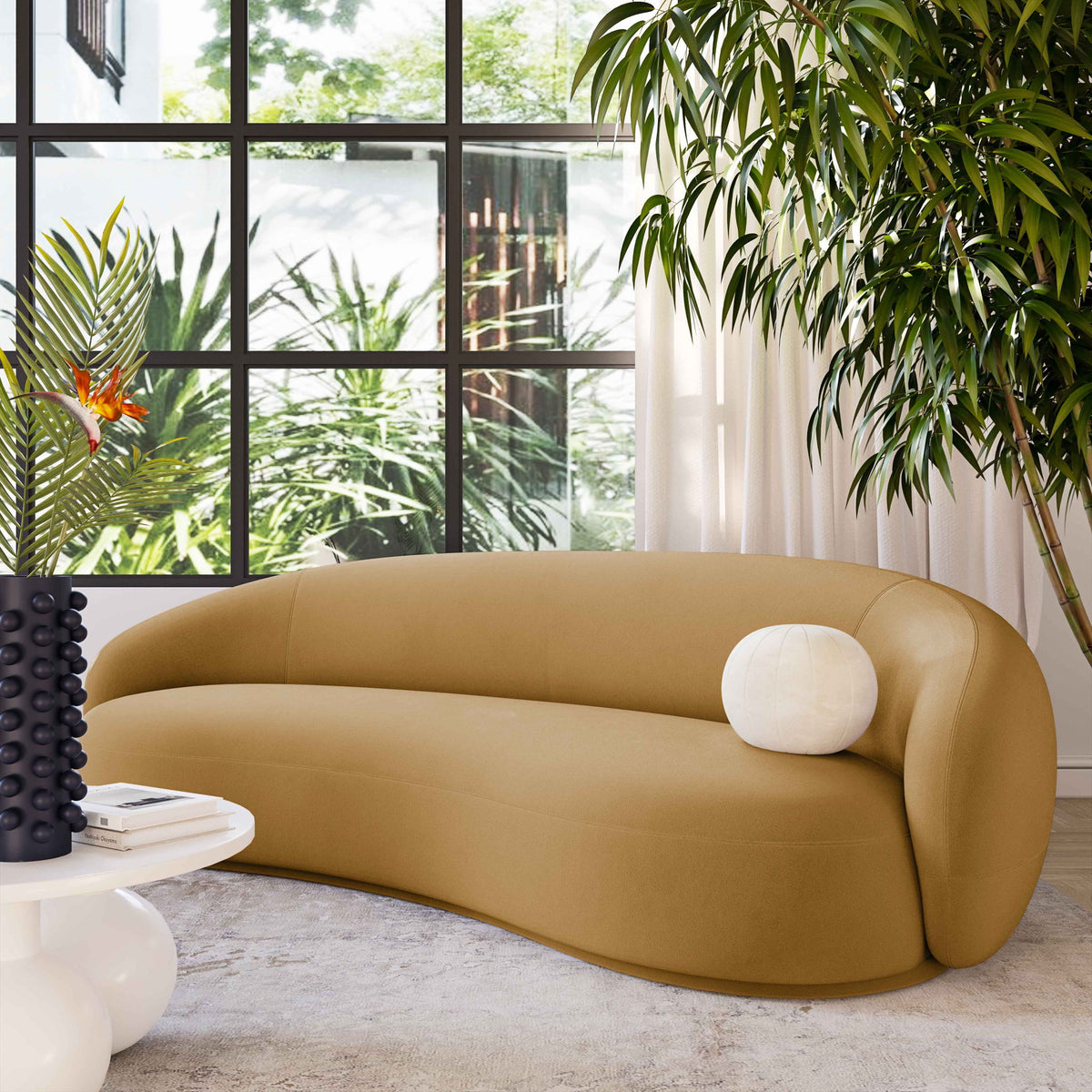 Tan velvet sofa with rounded back and white round accent pillow