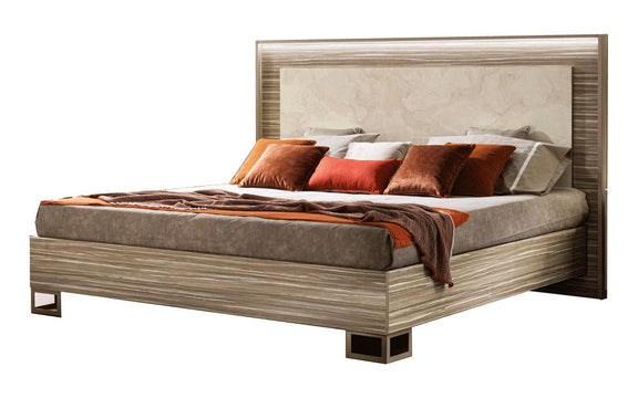Beige upholstered bed with wooden headboard and footboard, shown with pillows and throw