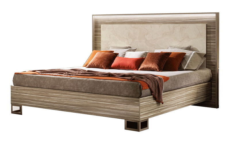 Beige upholstered bed with wooden headboard and footboard, shown with pillows and throw