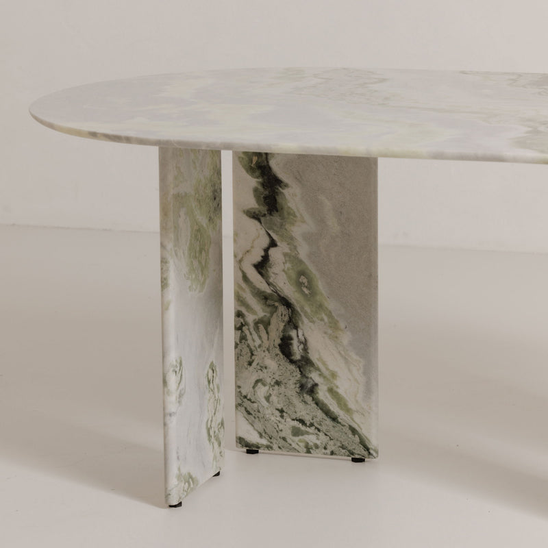 Close view of oval marble dining table top with green veining on pedestal base