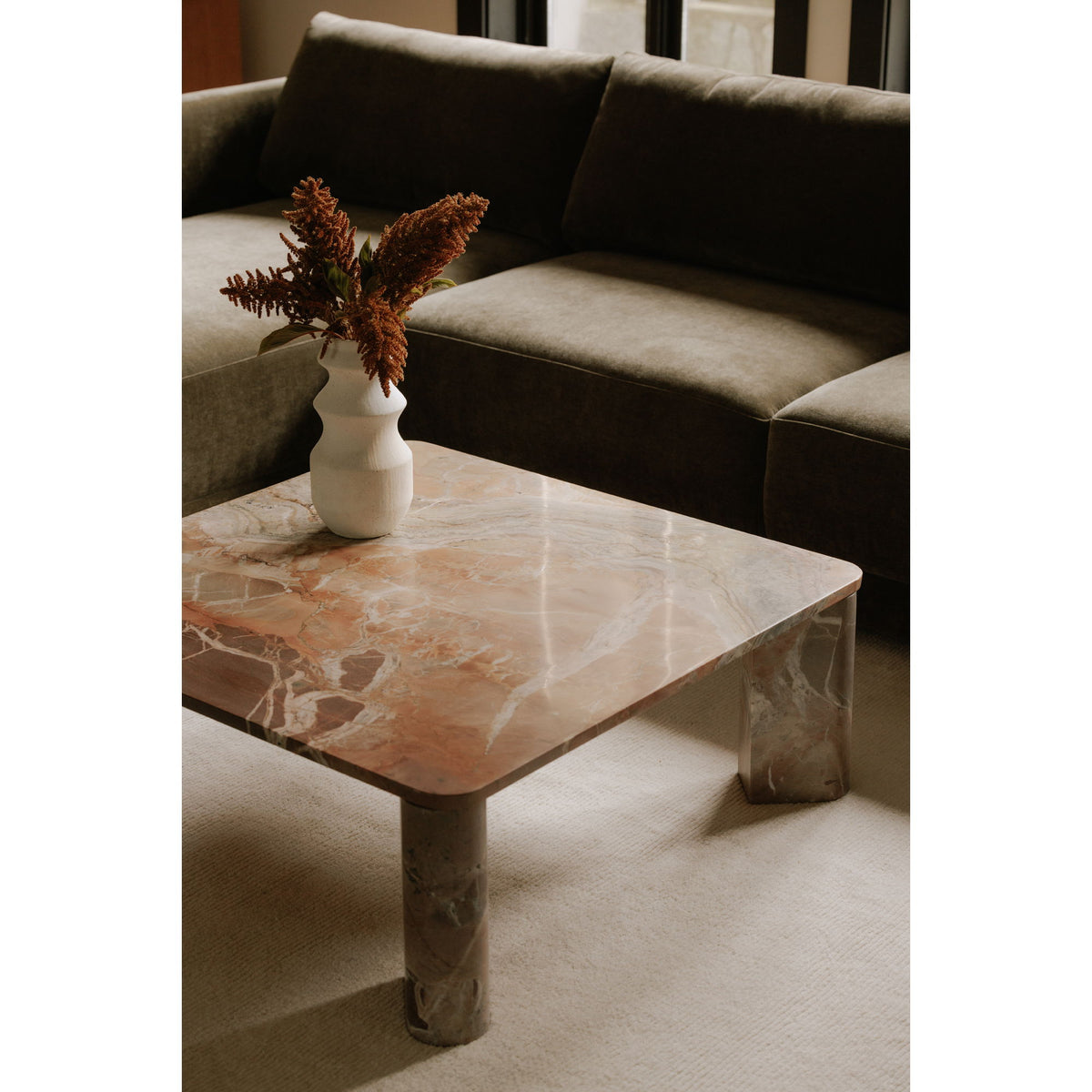 Orange marble coffee table corner view with veined tabletop and blocky legs