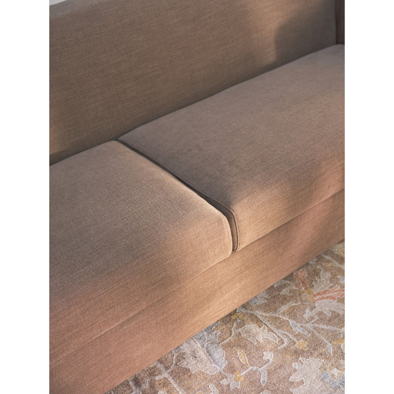 Soft brown sofa seat cushion detail with stitched seam and curved arm corner.