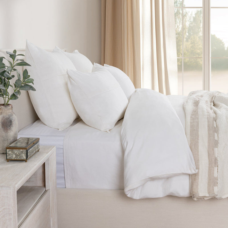 White linen sham pillows arranged on a sofa bed with matching bedding