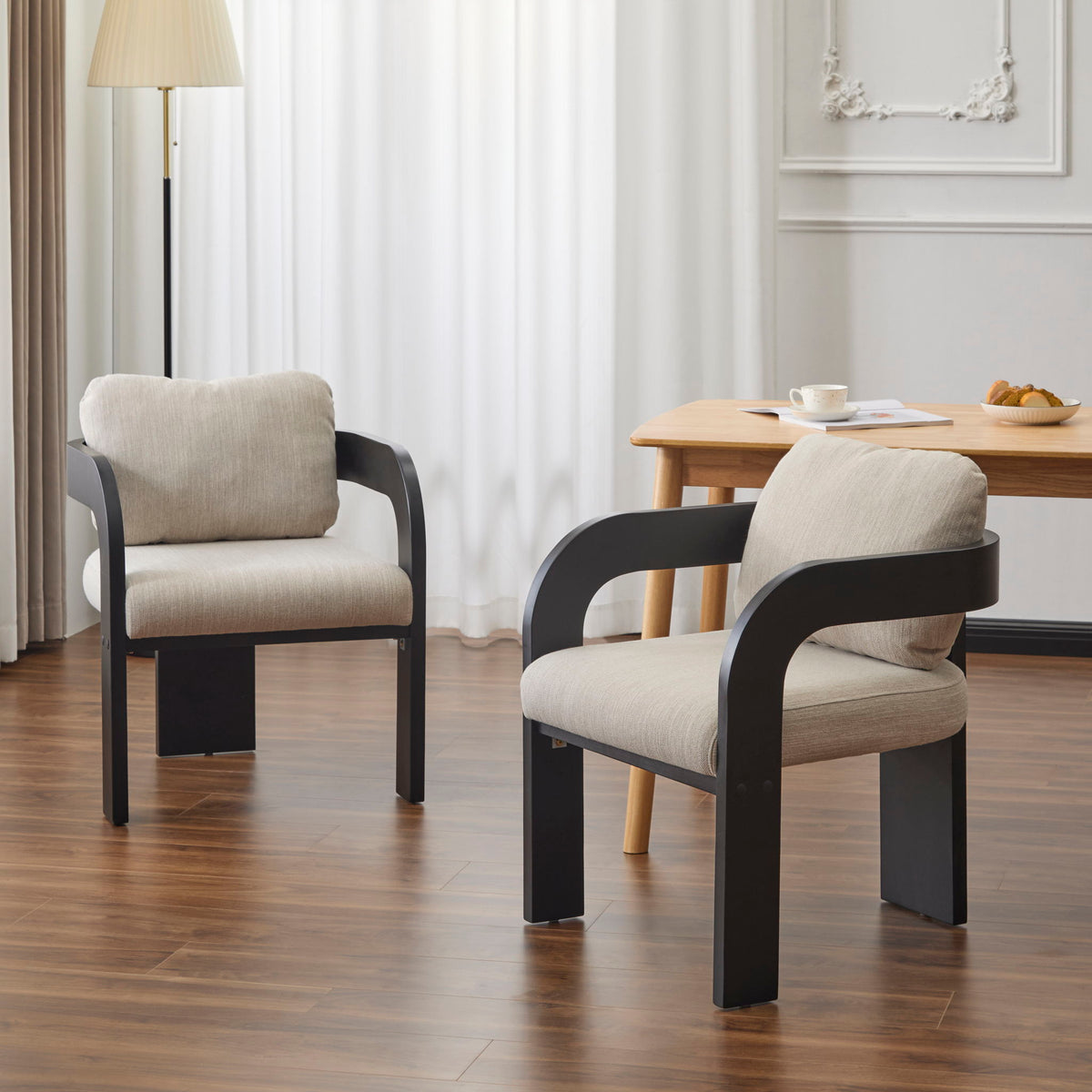 Pair of beige and black dining chairs with padded backs and seats and curved armrests
