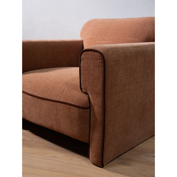 Light brown upholstered chair corner with rolled armrest and smooth seat cushion.