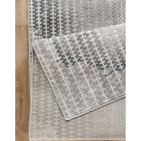 Gray area rug with woven 3D geometric pattern and textured pile detail.