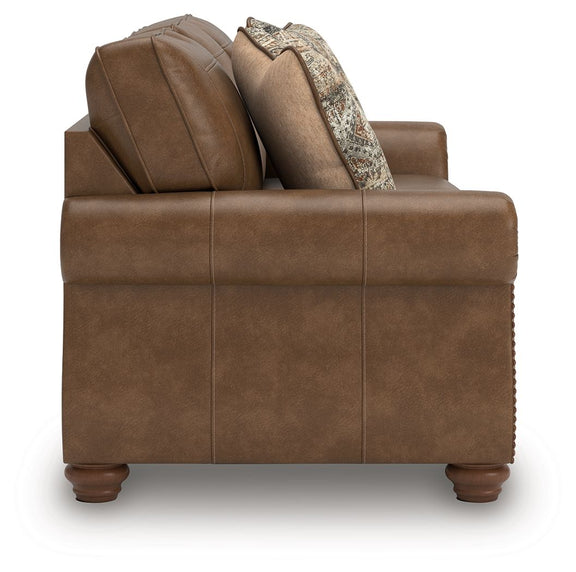 Brown sofa with tufted backrest and two patterned throw pillows