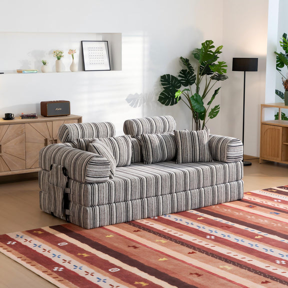 Convertible sofa bed with striped upholstery, armrests and back cushions, angled view