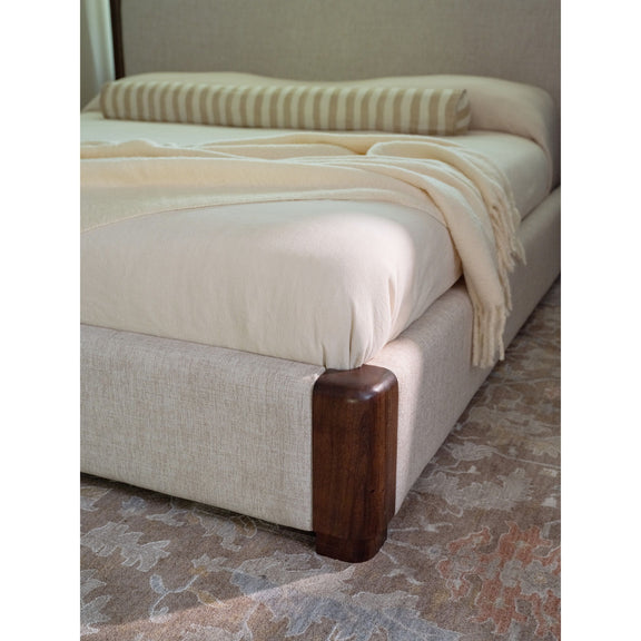 Queen bed upholstered base with brown wood corner legs and beige bedding