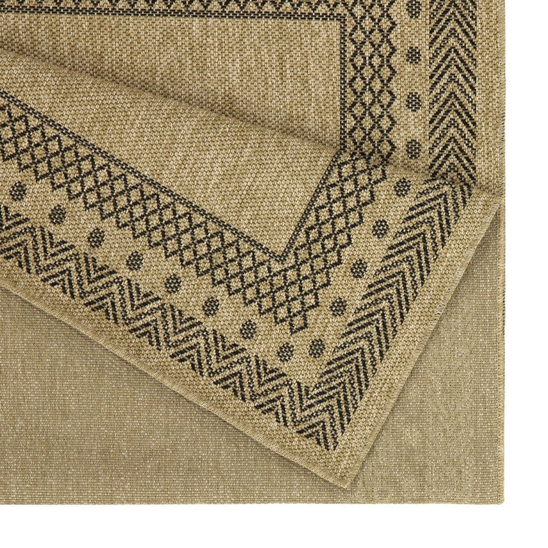 Corner close-up of light brown rug with dark zigzag pattern and woven texture.