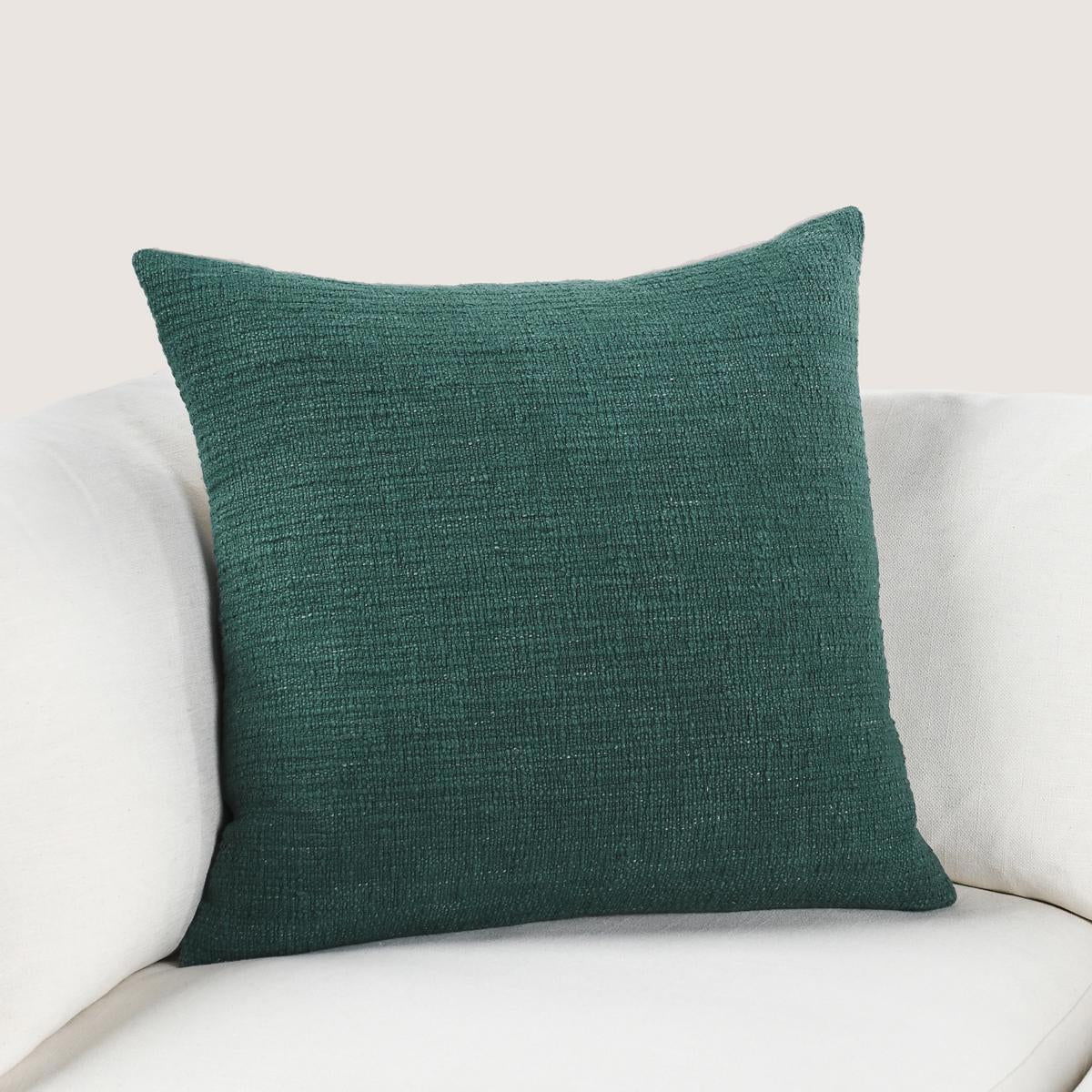 Jungle green textured throw pillow with squared corners on a sofa