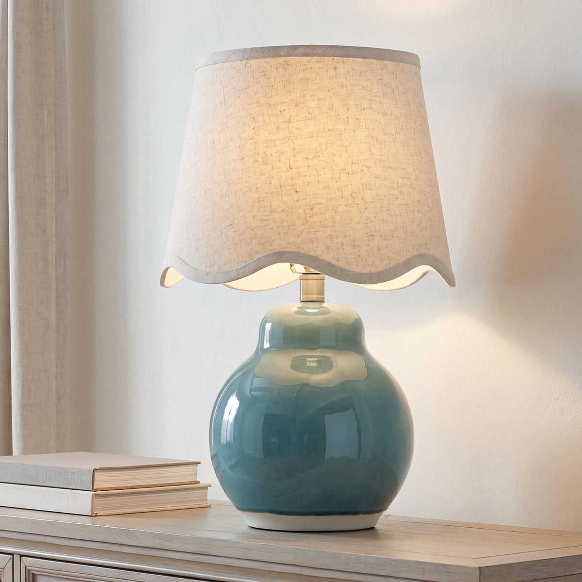 Teal ceramic table lamp with beige fabric shade on side table