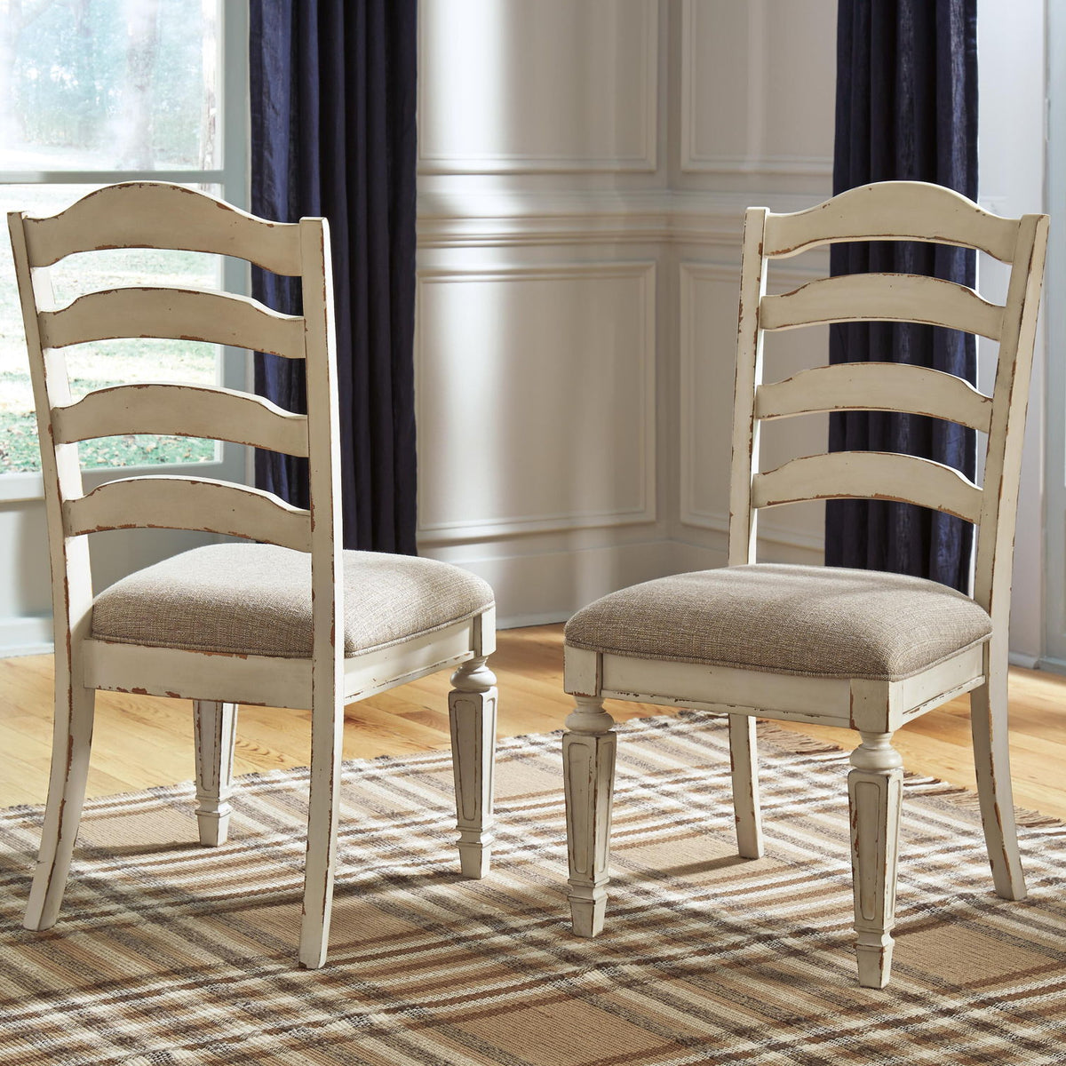 Pair of ladderback dining chairs with chipped white wood and taupe upholstered seat cushions.