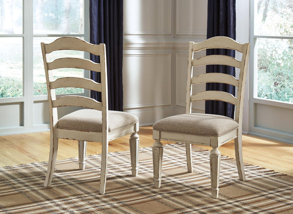 Pair of ladderback dining chairs with chipped white wood and taupe upholstered seat cushions.