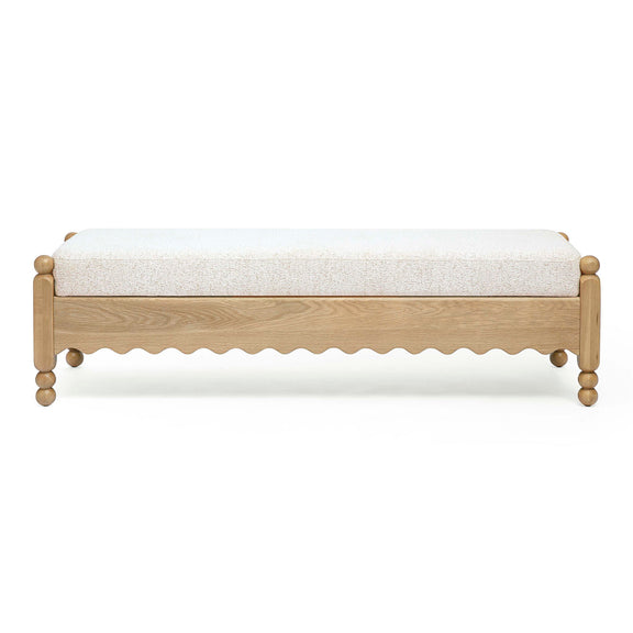 Cream bench with textured upholstery, light wood frame, scalloped apron and round legs.