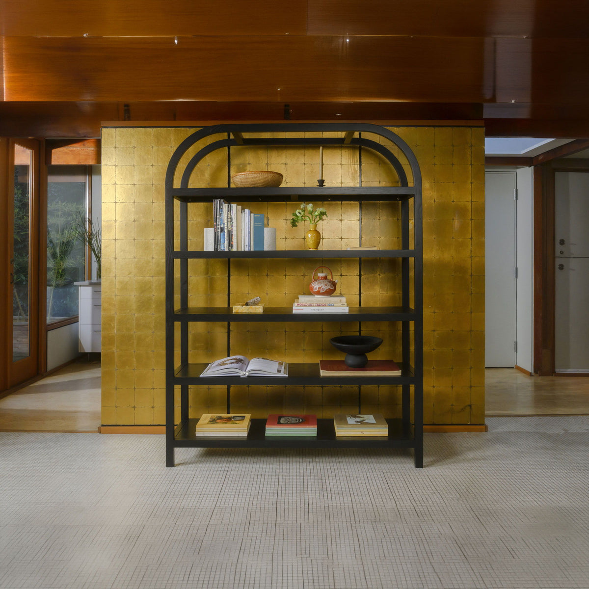 Black arched bookcase standing in a room, open shelving with books