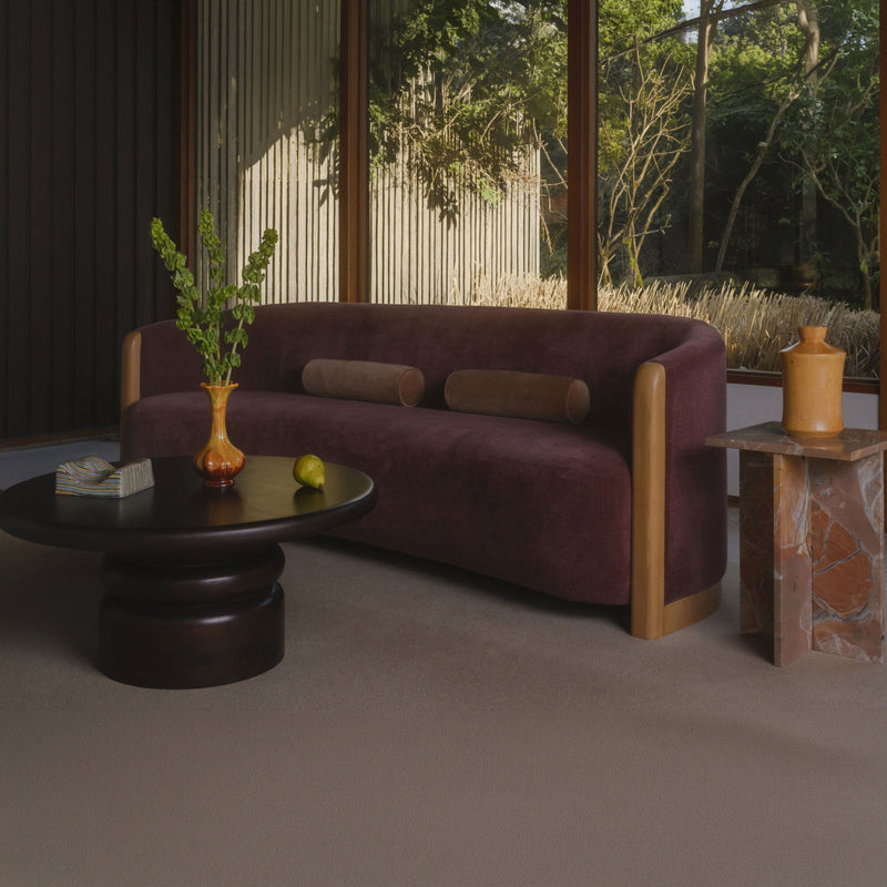 Berry purple upholstered sofa with rounded arms, light wood legs, and two cushions