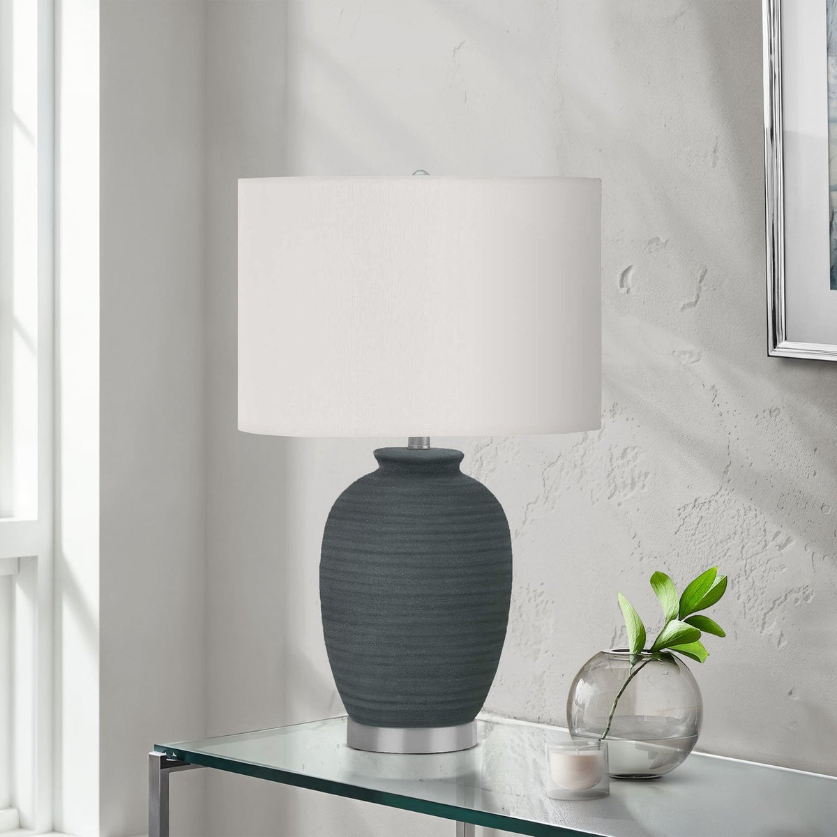 Dark blue ceramic table lamp with white shade on glass table