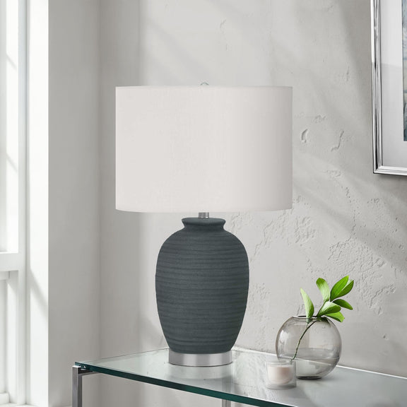 Dark blue ceramic table lamp with white shade on glass table
