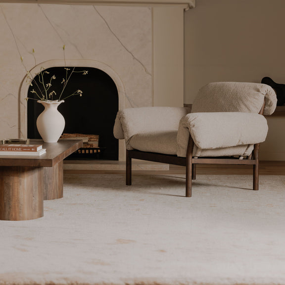 Beige lounge chair with cushioned arms and seat, dark wood frame and legs