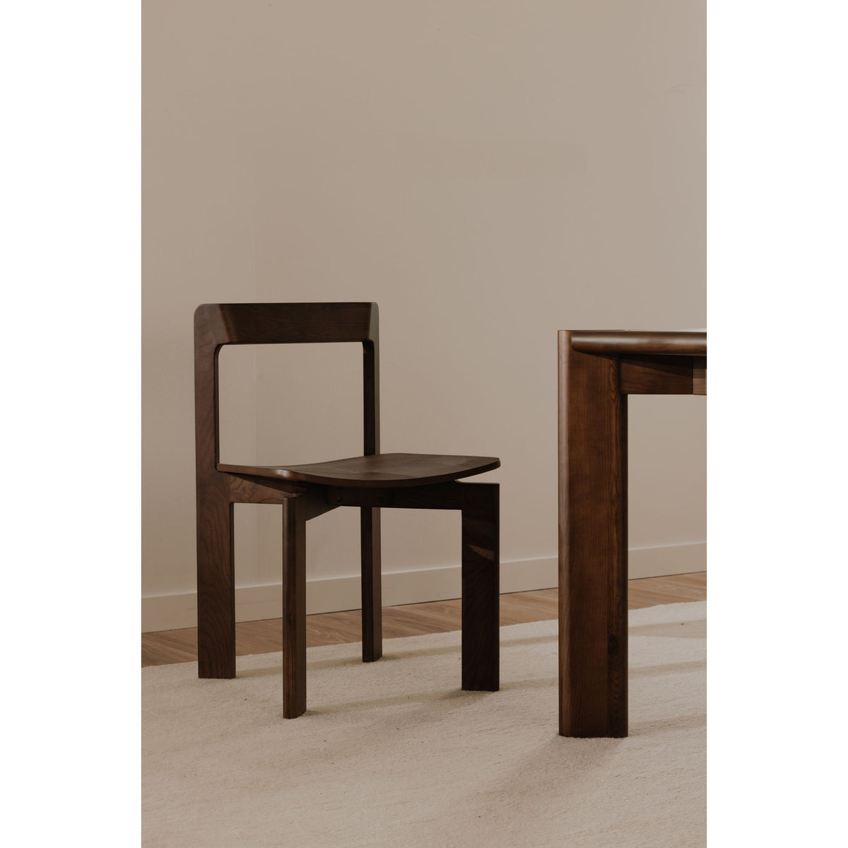 Walnut dining chair with open square back and dark wood seat, angled view