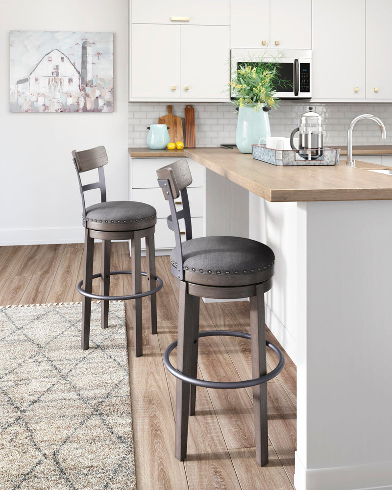 Two tall swivel barstools with gray upholstered round seats and nailhead-trimmed backs