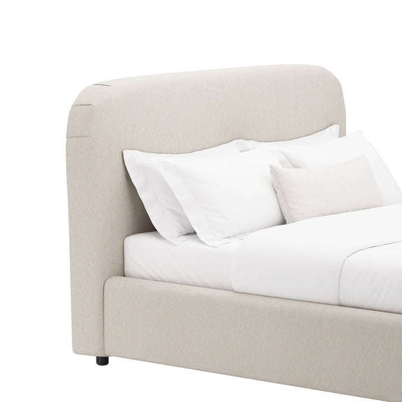 Beige rounded upholstered bed frame with curved headboard, white pillows, and tapered legs